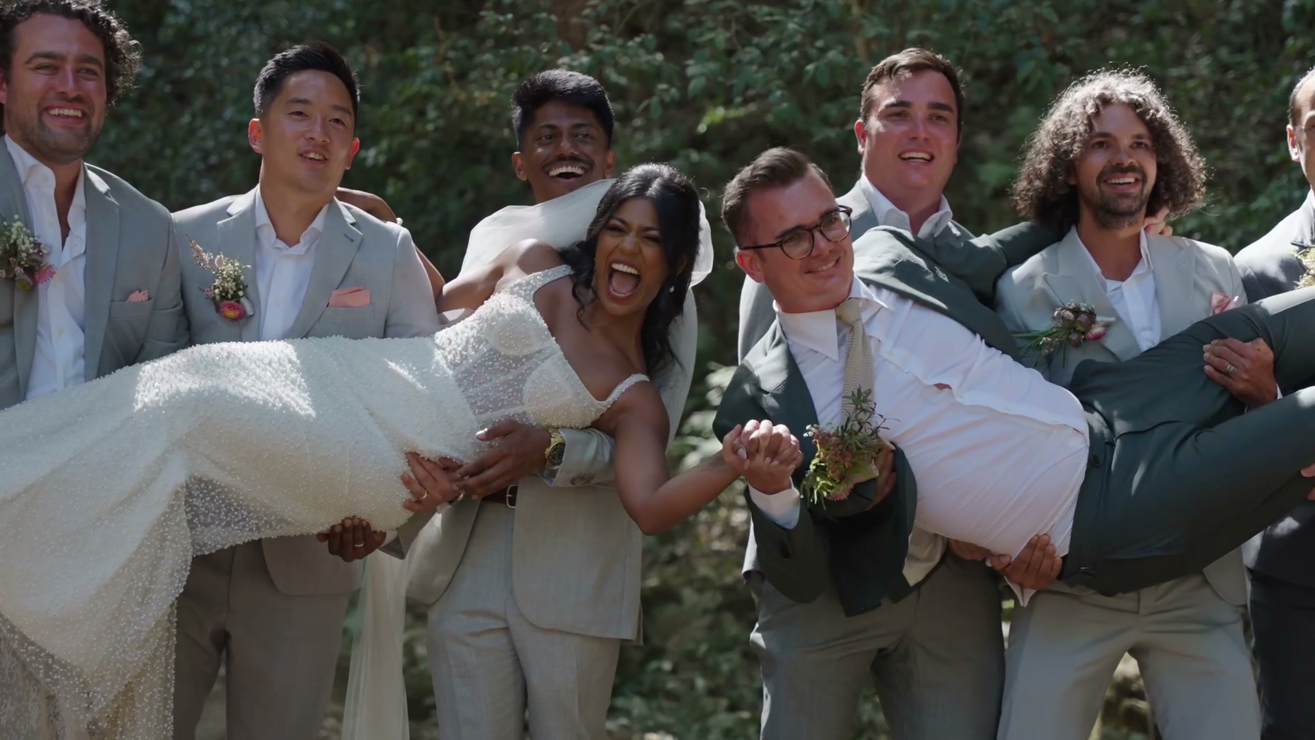 Riya & Matthias. A full 3 minute 29 second wedding film. Rings and flowers, vows read into a microphone across a bush valley, the bridal party carrying the bride, bridesmaids dancing in pink pleats, a black-and-white shot of the couple walking away as horses run past them, and a dance floor under magenta light.